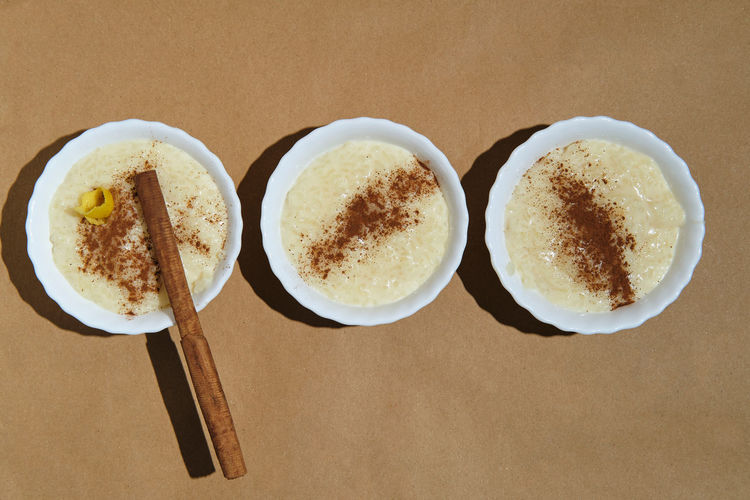 Zenithal plane of three rice pudding desserts on a brown background