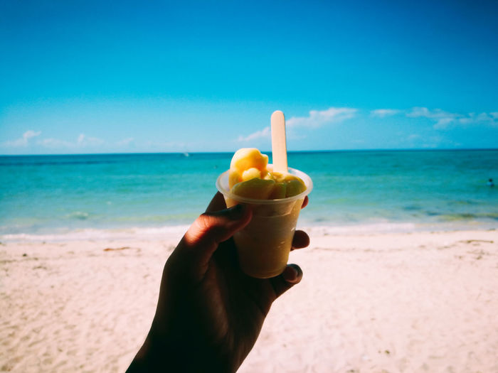 Close-up of person holding ice cream on beach