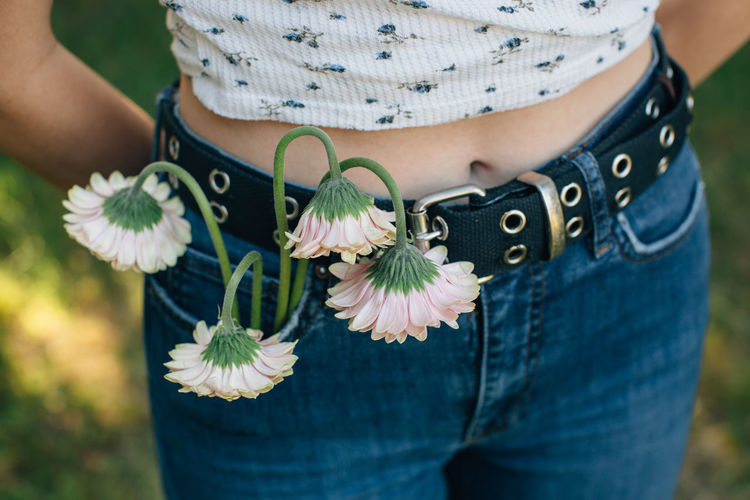 Close-up midsection of teenage girl with flowers in pocket outdoors