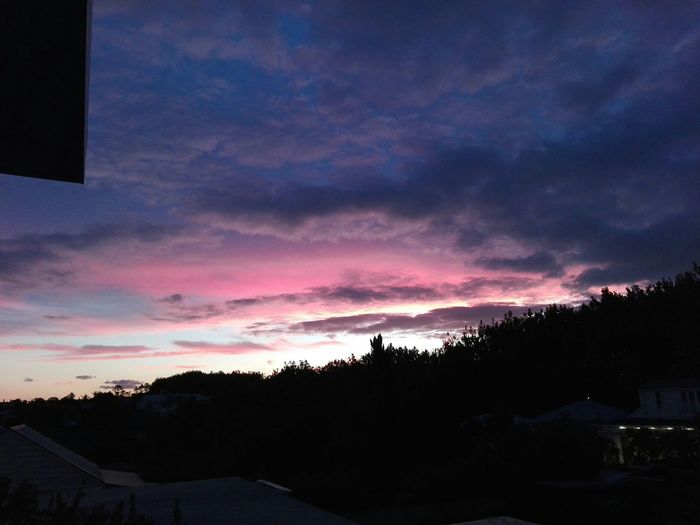 Silhouette houses against sky during sunset