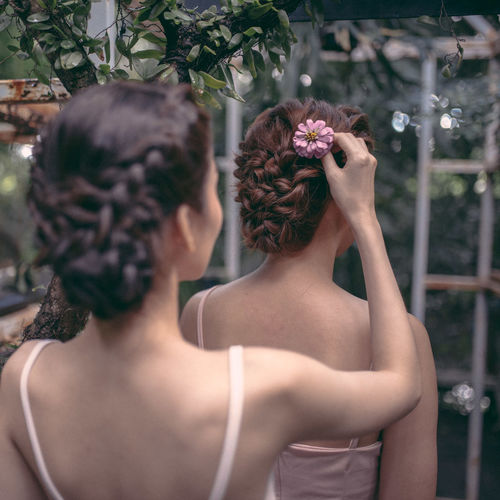 Rear view of woman adjusting flower on bride hair
