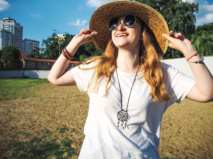 Smiling young woman wearing sunglasses and sun hat 