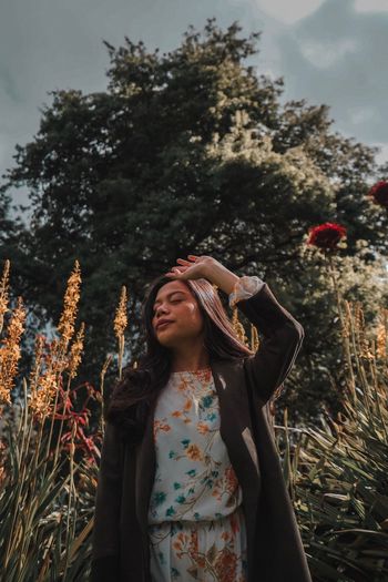 Young woman looking away while standing on tree
