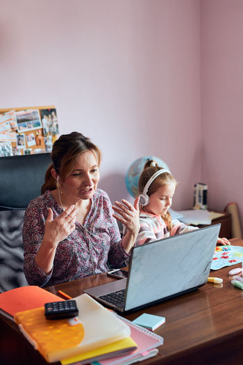 Mother working at home while daughter studying at home
