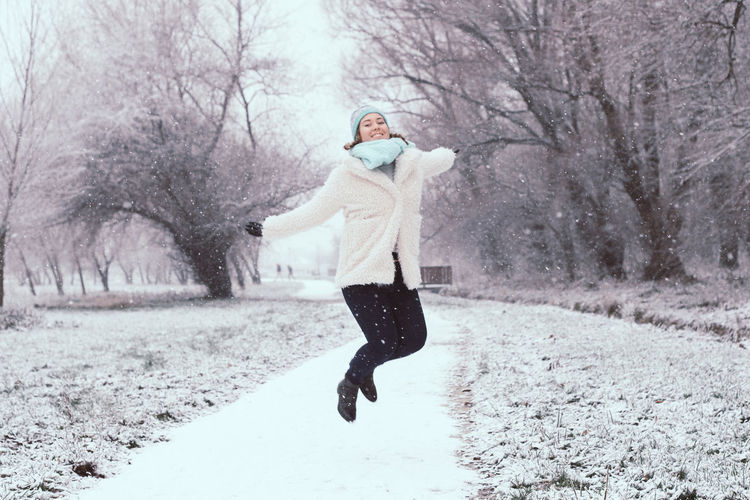 Happy young woman jumping at park during winter