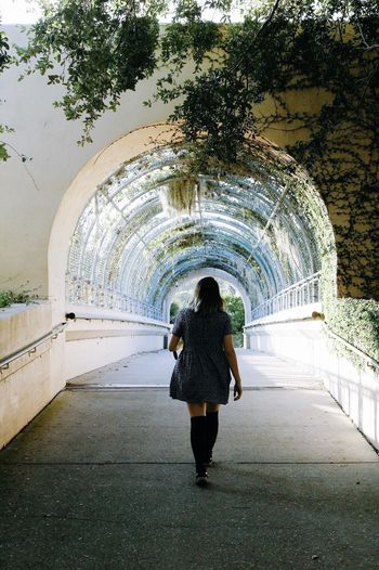 Rear view of woman walking on covered walkway at park