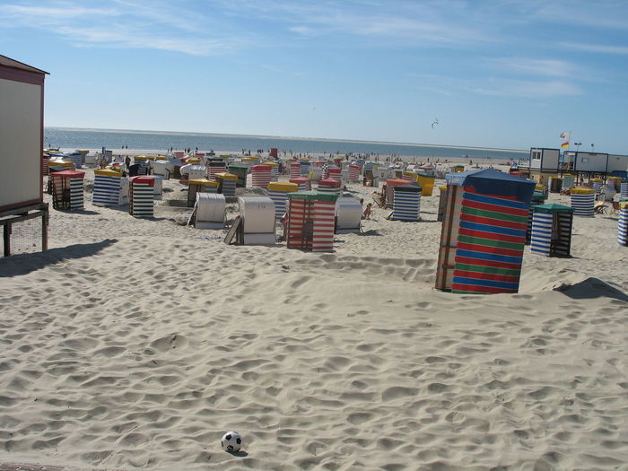 Hooded chairs on beach against blue sky