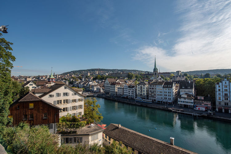 Buildings by river against sky in city