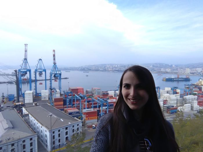 Portrait of smiling young woman standing against buildings in city
