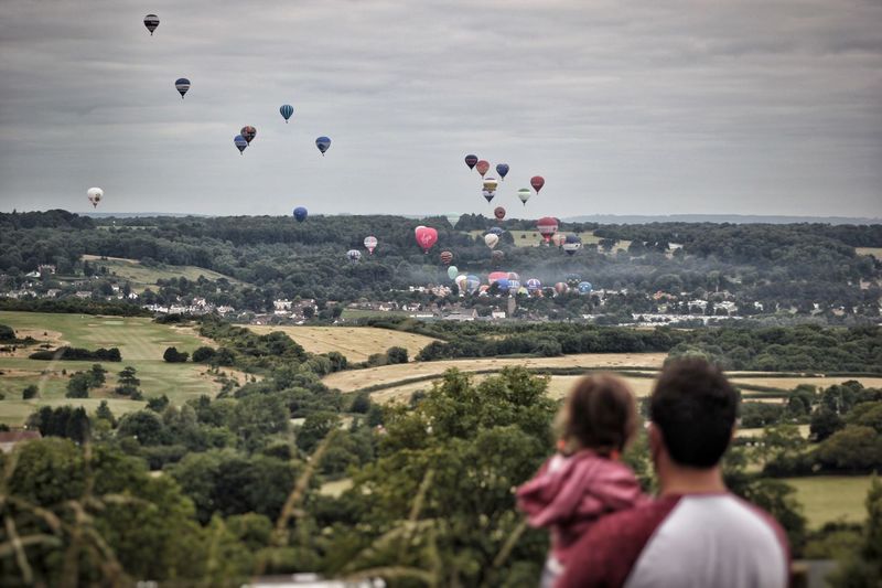 Rear view of father and daughter looking at hot air balloons during bristol international balloon fiesta