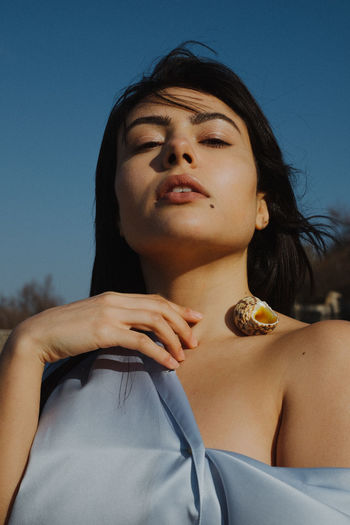Portrait of beautiful young woman with eyes closed against blue sky