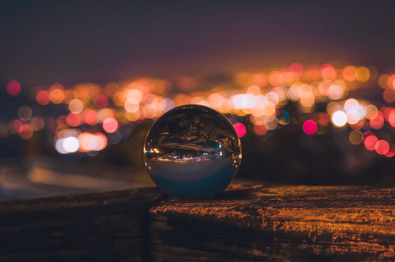 Close-up of crystal ball against cityscape at night
