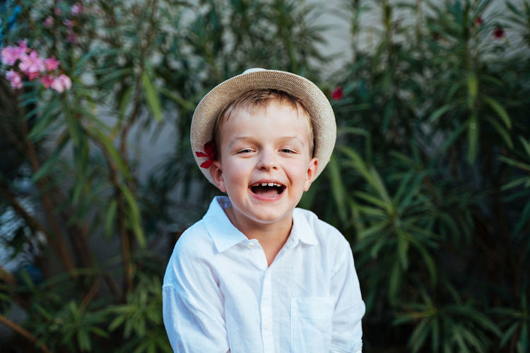 A boy in a straw hat and a white shirt is smiling. sincere laugh of a child. close-up portrait