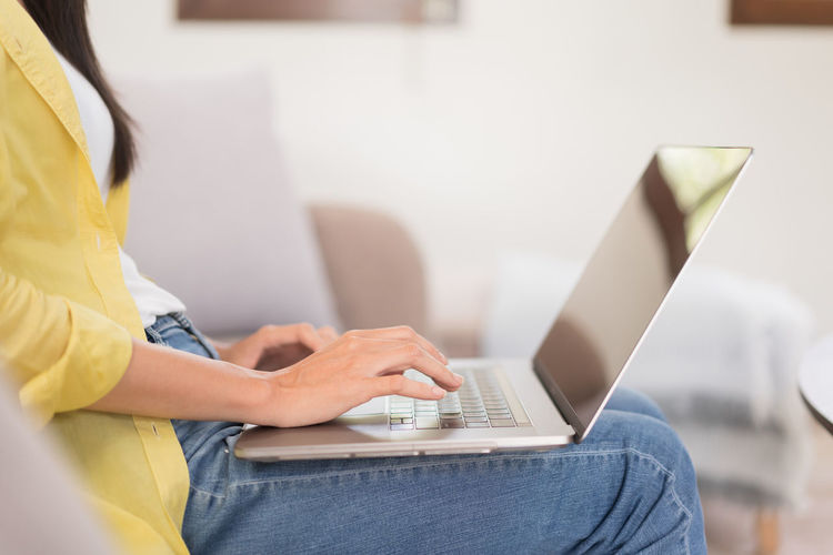 Midsection of woman using laptop at home