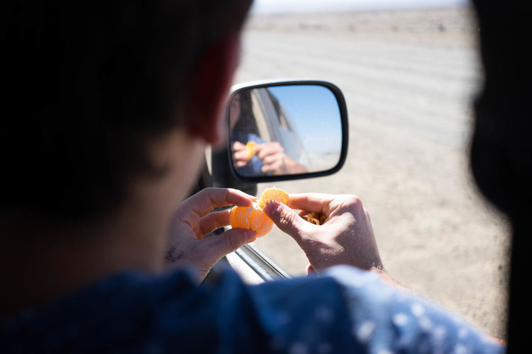 Midsection of man eating orange sitting in car
