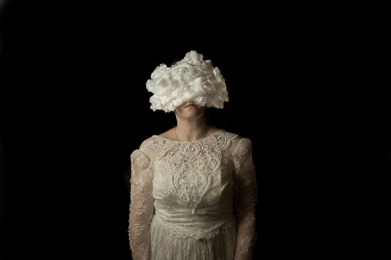 Woman with obscured face standing against black background