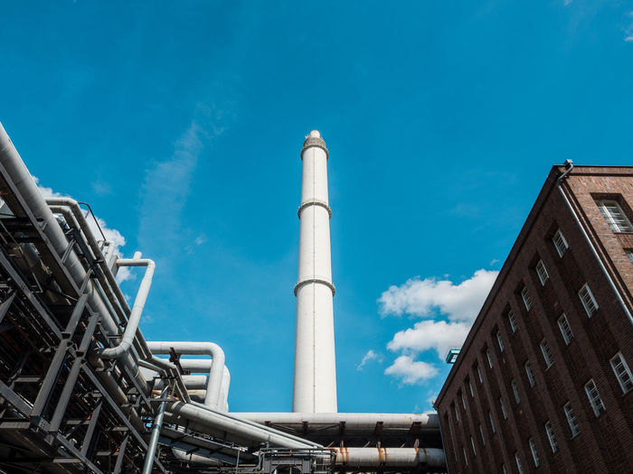 Low angle view of industry and chimney against sky