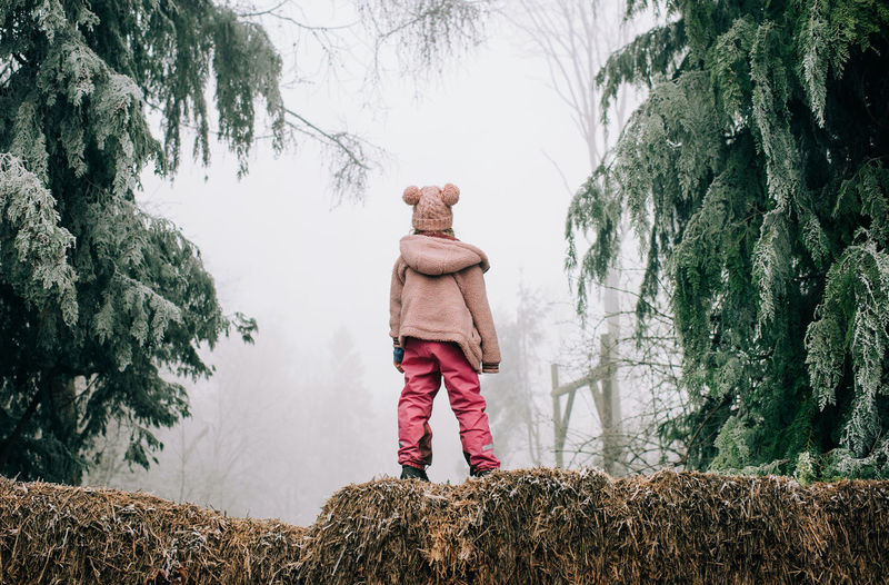 Girl stood in the frosty forest looking into the fog in england