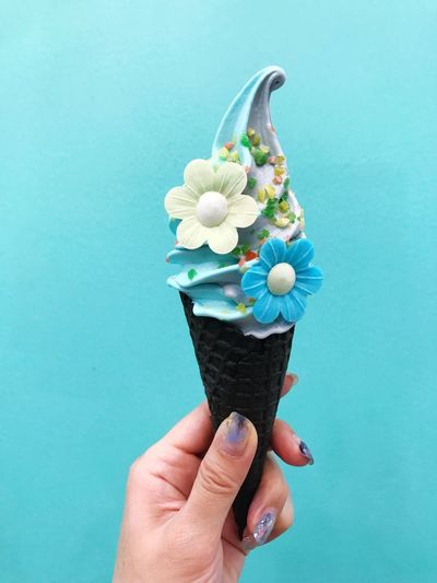 Close-up of hand holding ice cream against blue background