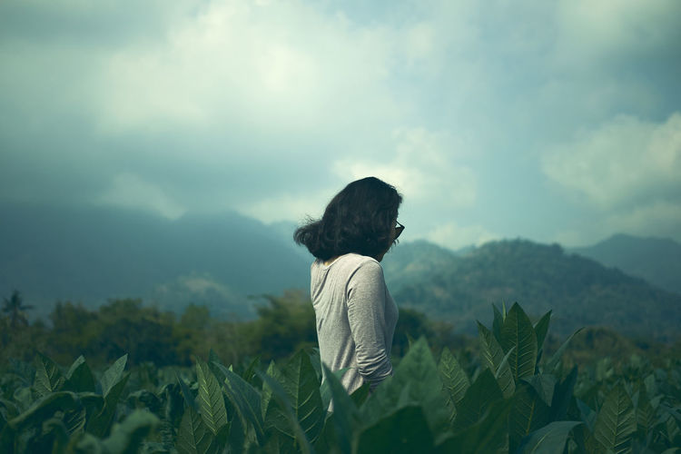 Side view of woman standing amidst plants