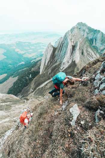 Two young women climbing steep terrain in front of steep mountains