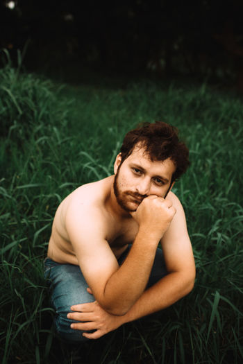 Portrait of young man sitting on field