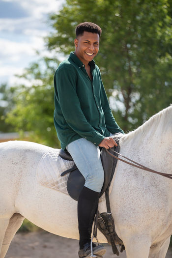 Smiling young woman riding horse