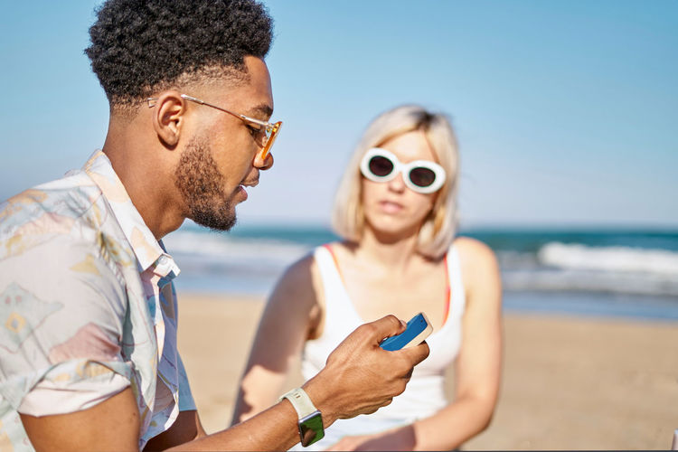 Side view of young man wearing sunglasses against sea