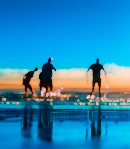 Silhouette people at beach against blue sky during sunset