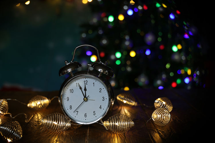 Close-up of illuminated christmas lights and clock on table