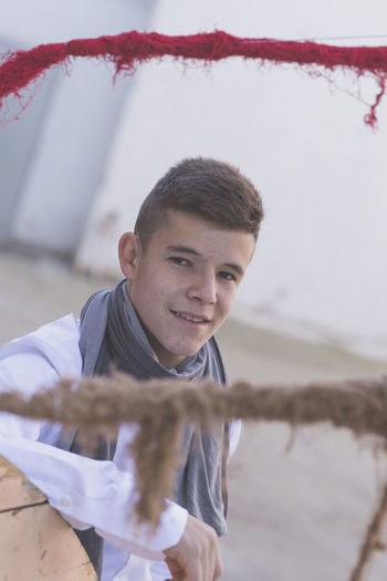 Portrait of teenage boy standing by large spool on footpath