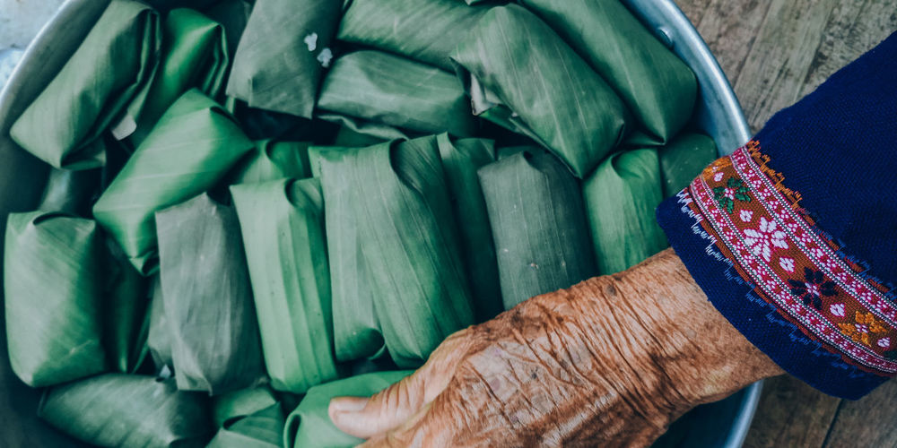 Cropped hand of woman holding food packed in leaf