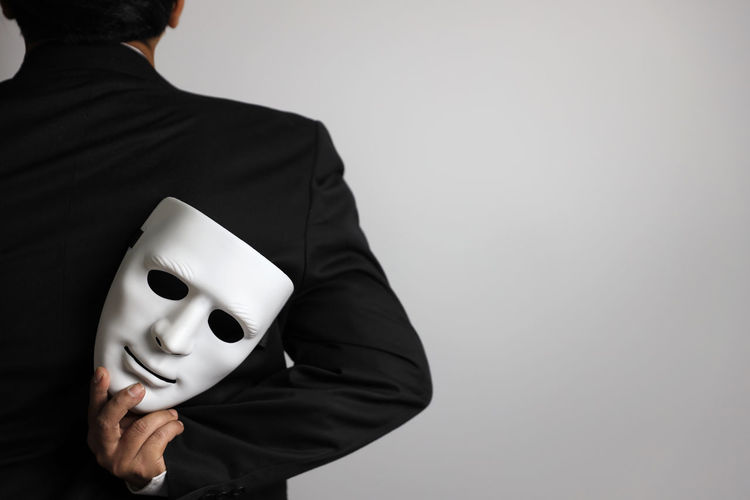 Midsection of person wearing mask against white background