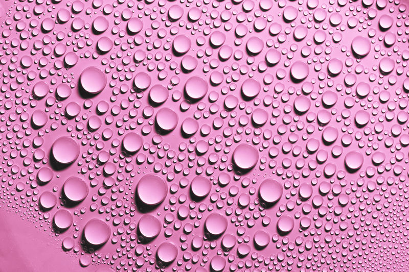 Detail and close up of condensation drops of pink water on surface. texture background decoration.