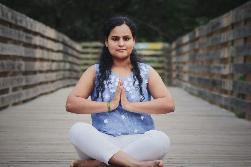 Full length portrait of young woman doing yoga on boardwalk