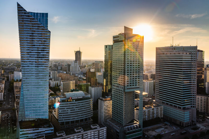 Modern buildings in city against sky during sunset