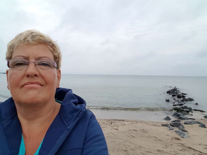 Portrait of mature woman at beach against sky