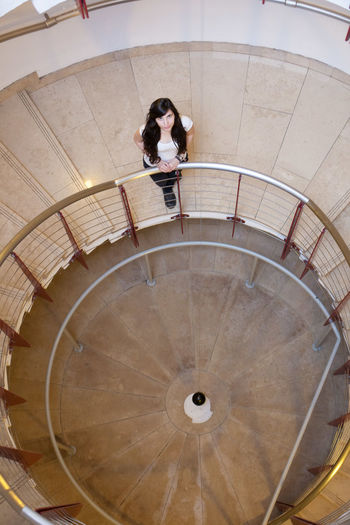 Low angle view beautiful young women lonely on spiral staircase with a foucault pendulum experiment