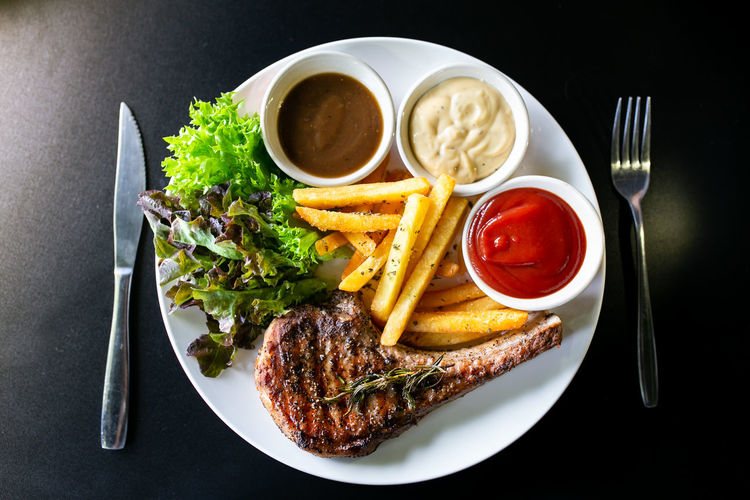 Grilled meat, porkchops steak with pepper sauce and salad.