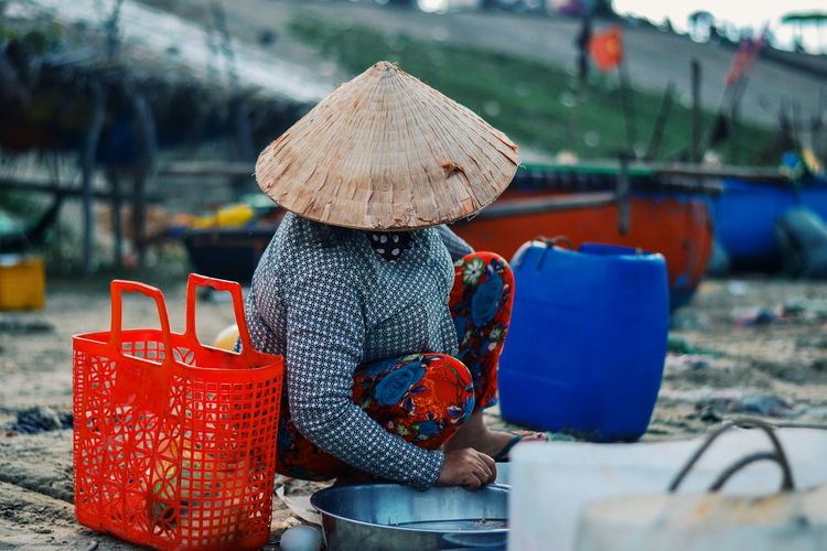 Woman crouching by red basket at fish market