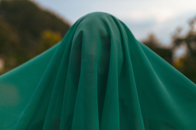 Close-up of woman with face covered by green scarf