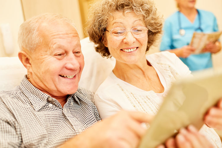 Happy senior couple using digital tablet at nursing home