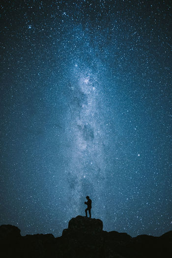 Low angle view of silhouette man standing against star field