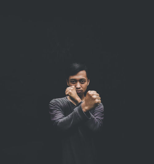 Portrait of man gesturing against black background