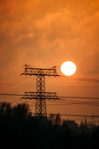 Low angle view of silhouette electricity pylon against sky during sunset