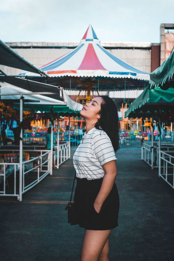 Side view of young woman standing at amusement park