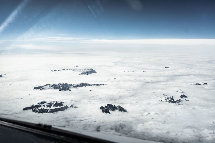 Aerial view of snow covered land against sky