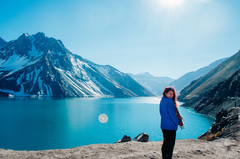 Portrait of smiling woman standing against lake and mountains