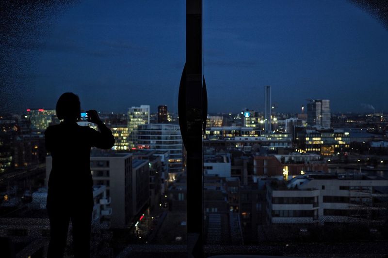 Rear view of woman looking at illuminated cityscape against sky at night