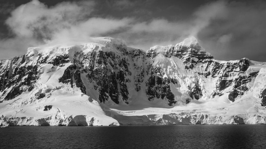 Black and white photo of glacier against snowcapped mountain in antarctica